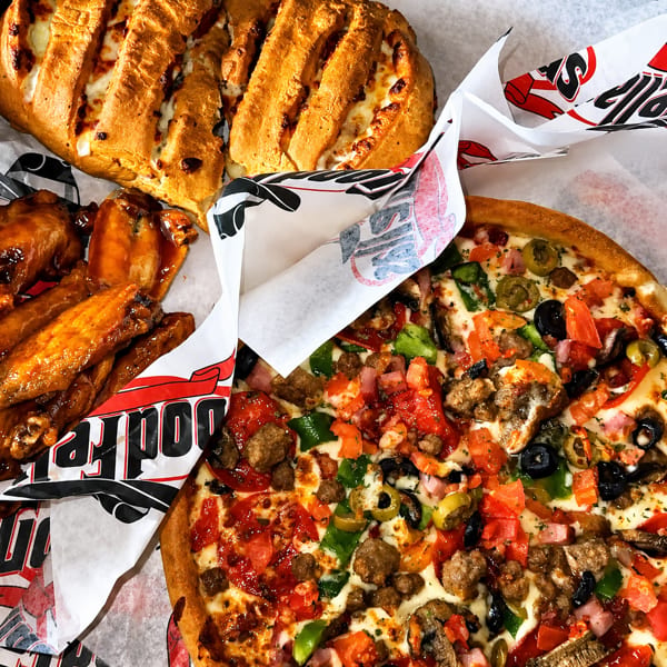 Cheesy loaded pizza, glazed chicken wings, and a toasted stuffed bread served on branded paper.