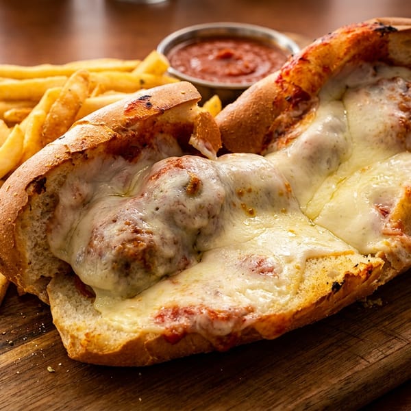 Meatball sub with melted cheese and marinara, served with french fries and dipping sauce.