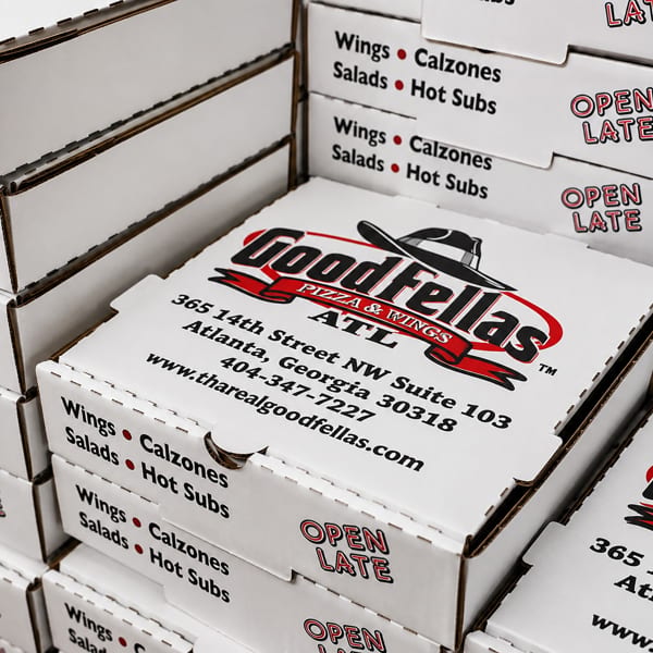 Stacked Goodfellas Pizza & Wings boxes display the Atlanta address, website, menu categories, and “Open Late” text.